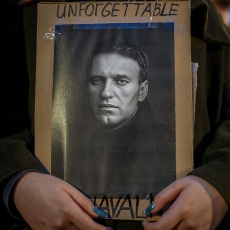 Eine Frau hält zum Gedenken an den Tod von Alexej Nawalny ein Foto von ihm in den Händen. 