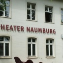 Weiße Hausfassade eines Altbaus, Theater Naumburg steht darauf in roten Blechbuchstaben, das Gebäude ist von grünen Blättern umrankt