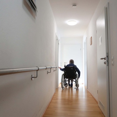 Symbolbild: Ein Mensch in einem Rollstuhl am Ende eines leeren Flures.