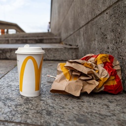 Pappbecher und Fast-Food-Verpackung auf einer Treppe.