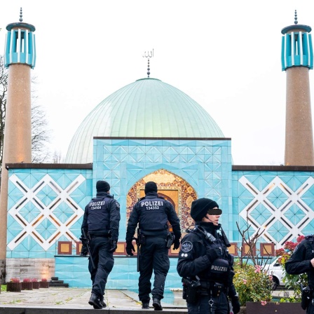 Einsatzkräfte der Polizei stehen während einer Razzia beim islamischen Zentrum Hamburg vor der Imam Ali Moschee (Blaue Moschee) (Bild: dpa / Daniel Bockwoldt)