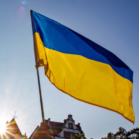 Jemand hält eine ukrainische Flagge hoch.