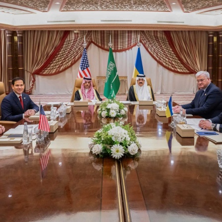 Vertreter von USA, Ukraine und Saudi-Arabien sitzen bei den Verhandlungen in Jeddah am Konferenztisch.