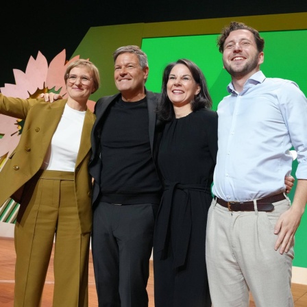 Felix Banaszak, Annalena Baerbock, Robert Habeck und Franziska Brantner jubeln gemeinsam auf einer Bühne bei der 50. Bundesdelegiertenkonferenz der Grünen in Wiesbaden.