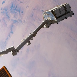 Ein Roboterarm hält eine alte Batterie der Weltraumstation ISS.
