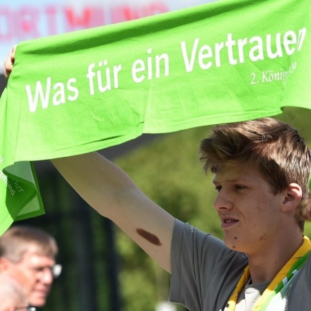 Ein junger Mann hält während des Evangelischen Kirchentages in Dortmund vor der Westfalenhalle einen grünen Schal mit der Aufschrift «Was für ein Vertrauen» hoch. Gut 2000 Veranstaltungen sind bis zum 23. Juni 2019 geplant, zahlreiche Politiker und