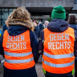 Teilnehmer einer Demonstration tragen orange Westen mit der Aufschrift "Gegen Rechts"