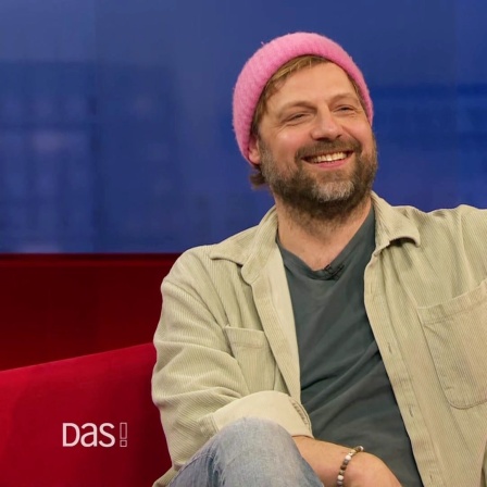 Christoph Letkowski auf dem roten Sofa.