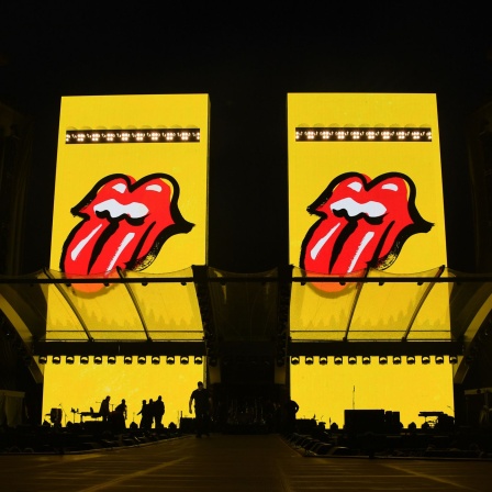 Ein Bühnbild der Rolling Stones zeigt vier herausgestreckte Zungen, das Markenzeichen der Band (Bild: dpa / Carsten Rehder)