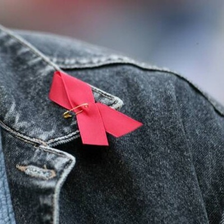 Rote Aidsschleife auf schwarzer Jeansjacke