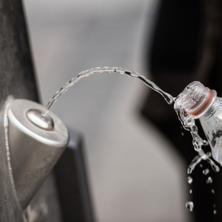 in Mann füllt sich an einem Brunnen kostenlos Trinkwasser in seine Flasche