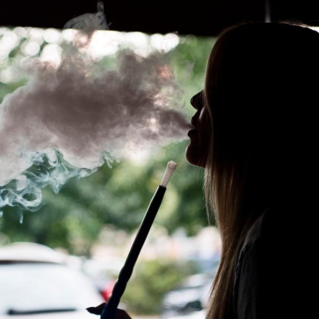 Eine junge Frau raucht in einer Shisha-Bar in Berlin eine Shisha-Pfeife.