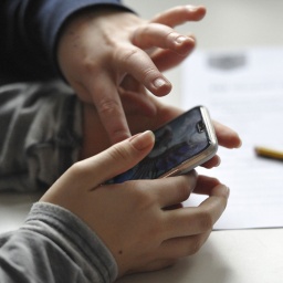 Zwei Menschen tippen auf einem Smartphone.