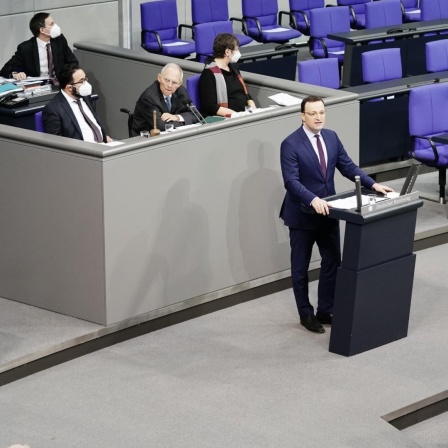 Jens Spahn (CDU), Bundesminister für Gesundheit, gibt eine Regierungserklärung zu Corona-Impfungen im Bundestag ab. Links sitzt Bundeskanzlerin Angela Merkel (CDU).