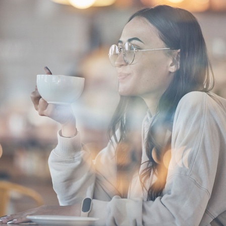 Eine Frau trinkt einen Kaffee in einem Café.