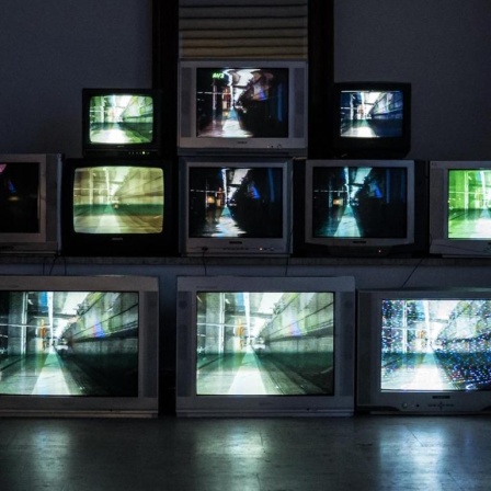 Vernissage der "TV WALL digital to analog" Ausstellung in der Kunstgalerie Scheier, Kroatien, eine Pyramide aus laufenden Fernsehgeräten steht in einem abgedunkelten Raum.