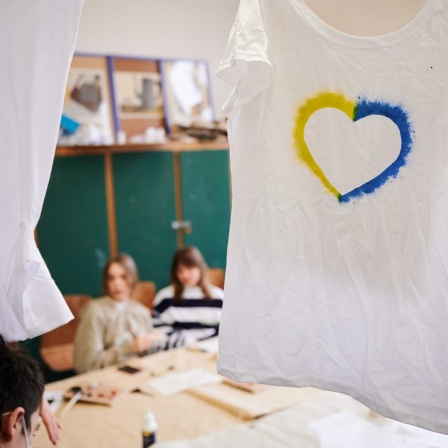 Ein T-Shirt mit einem Herz, umrahmt von den ukrainischen Farben hängt im Klassenraum einer Willkommensklasse am Willy-Graf-Gymnasium in Berlin-Lichterfelde. 
