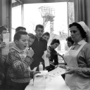 Eine Schwarz-Weißaufnahmen von 1962, zeigt Schulkinder, die unter Aufsicht einer Krankenschwester mit Impfstoff gegen Polio präparierte Zuckerwürfel einnehmen. 