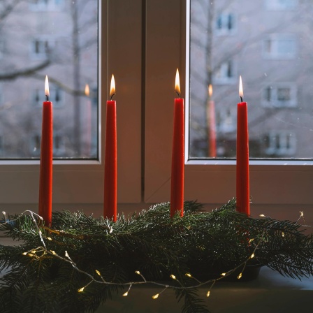 Ein Weihnachtsgesteck mit Tannenzweigen und Kerzen.