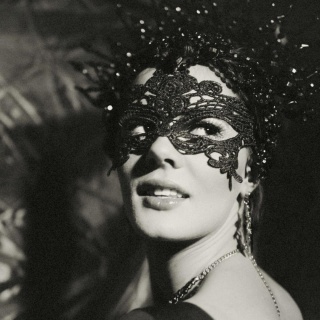 Schwarz-Weiß-Porträt eines Revue-Showgirls mit Maske vor den Augen.