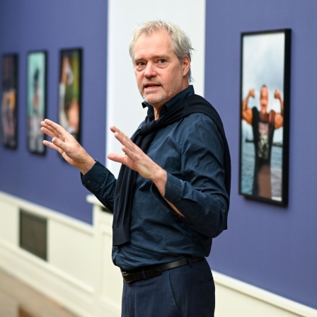 Vor Fotos der Ausstellung "Helmut Newton.Brands" erklärt Matthias Harder, Direktor der Helmut Newton Stiftung