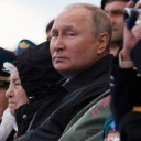 Russlands Präsident Wladimir Putin sitzt gemeinsam mit anderen Besuchern auf einer Tribüne und beobachtet die Militärparade am 9. Mai in Moskau.