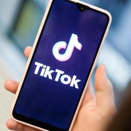 Ein Mädchen hält ihr Smartphone in den Händen, auf dem sie ein Foto der Kurzvideo-App TikTok geöffnet hat, 13.11.2019