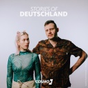 Die Hosts des Podcasts "Stories of Deutschland" Sina und Marius vor einer grauen Wand.