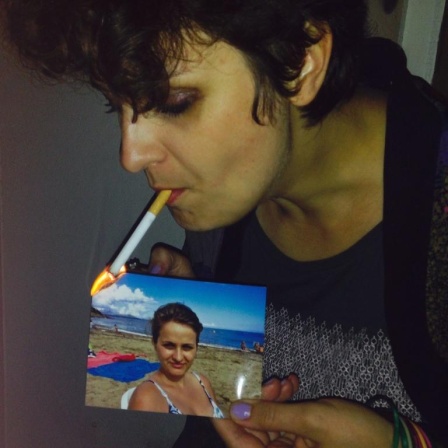 Eine Frau zündet mit ihrer Zigarette ein Bild von sich aus der Vergangenheit an.