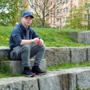 Ein Jugendlicher sitzt auf einer Steintreppe in einer Parkanlage
