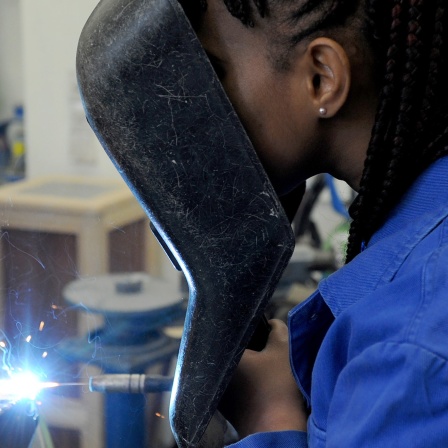 Junge Frau aus dem Guinea schweißt in einer Metallwerkstatt
