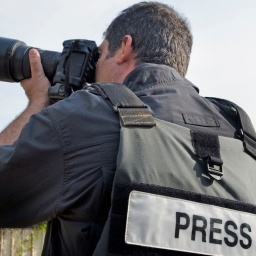 Professioneller Photojournalist mit einer Weste mit Aufdruck "Press" fotografiert.
