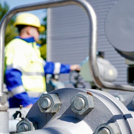 Ein Mitarbeiter der Firma Enovos Storage GmbH in Frankenthal (Rheinland-Pfalz) steht auf dem Gelände des Gasspeichers hinter Rohren einer Verdichteranlage. 