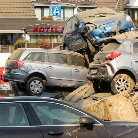 Zerstörte Fahrzeuge liegen aufgestapelt am Straßenrand auf Sperrmüllbergen.