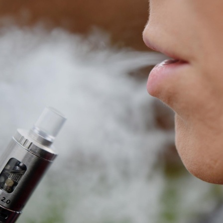 Eine Frau atmet Dampf einer E-Zigarette aus