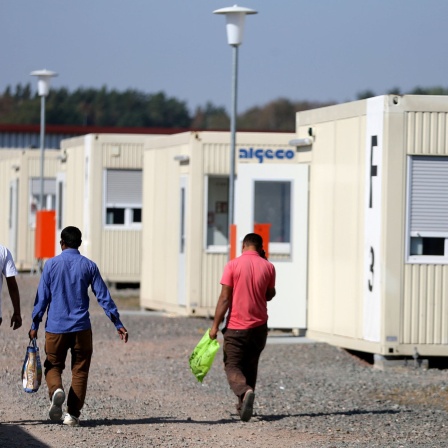 Geflüchtete laufen durch eine Flüchtlingsunterkunft