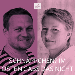 Auf dem Bild sind zwei Gesichter in Großaufnahme zu sehen, die einander zugewandt sind, vor einem lilafarbenen Hintergrund. Unten im Zentrum ist die Schrift "Schnaps? Das gabs im Osten nicht" zu lesen