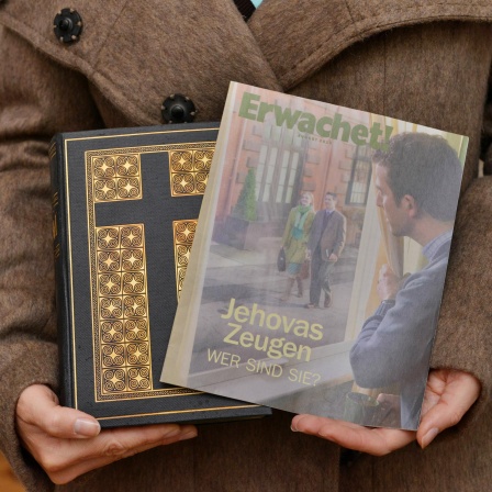 Ein Zeuge Jehovas mit Bibel und Broschüre "Erwachet" in der Hand.