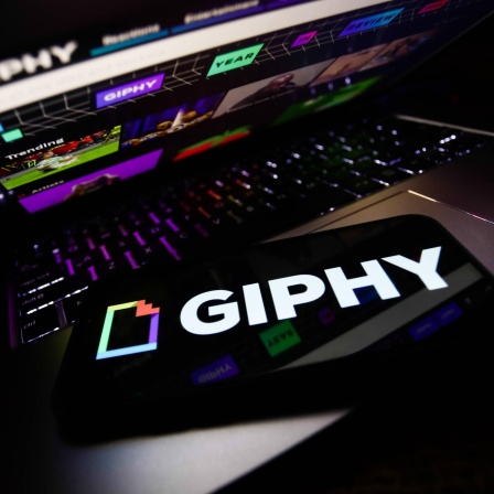 Ein Handy mit dem Giphy-Logo liegt auf einem Laptop, auf dem Giphy aufgerufen ist.