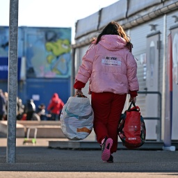Mit Gepäck gehen zwei Frauen durch eine Aufnahmeeinrichtung für Geflüchtete aus der Ukraine in Leipzig.