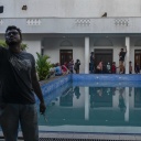 Vorne macht ein Demonstrant ein Selfie, im Hintergrund der Pool und der Palast des Präsidenten