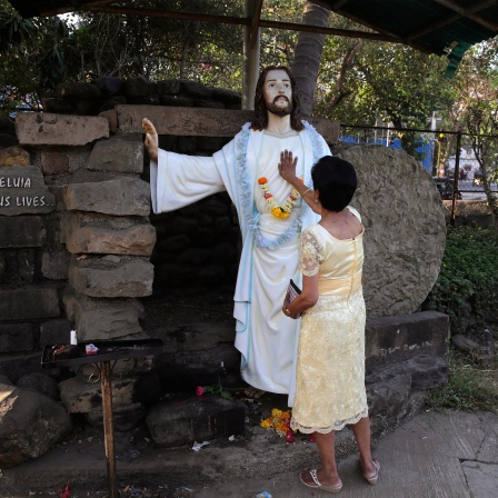 Eine gläubige Christin betet während einer Ostermesse an einer Kirche zu einer Statue von Jesus