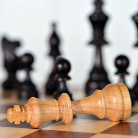 Die Schachfigur Weißer König liegt auf einem Schachbrett.