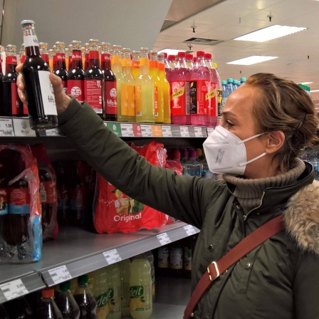 Eine Frau mit FFP2-Maske kauft im Supermarkt ein.