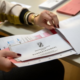 Eine Verwaltungsmitarbeiterin steckt Unterlagen für die Neuwahl zum 21. Deutschen Bundestag in einen Umschlag (gestellte Szene).