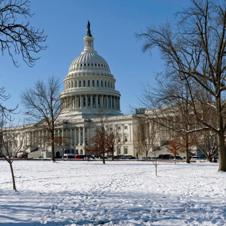 Das US-Kapitol in Washington (USA) ist an einem sonnigen Wintertag hinter eine mit Schnee bedeckten Wiese zu sehen.