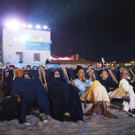 Während der 78. Internationalen Filmfestspiele in Cannes, Südfrankreich, sehen sich Menschen einen Film am Strand an.