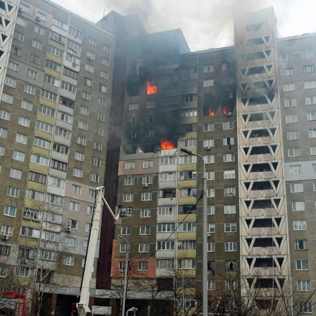 Feuerwehrleute löschen ein Feuer in einem Wohnhausin Kiew nach einem russischen Angriff.