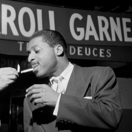 Szene aus dem Film "Misty - The Erroll Garner Story": Ein Mann zündet einem anderen eine Zigarette an. Im Hintergrund ist auf einer Werbetafel der Schriftzug "Erroll Garner" zu sehen.