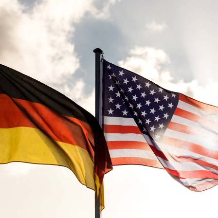 Fahne der Bundesrepublik Deutschland und der USA wehen bei aufziehenden Wolken im Wind